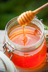 Honey in glass jar on a wooden floor.