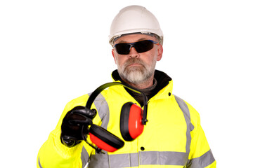 construction worker in a white hat,  yellow hi-viz coat and dark tinted safety glasses on white background gives foam-filled padded ear defenders to viewer Wear hearing protection 