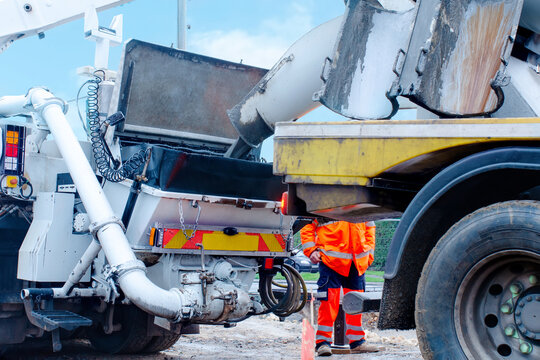 Concrete is offloaded from a concrete mixer into a concrete pump. Loading wet concrete into  pump