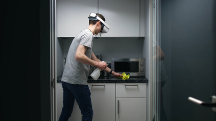 Young man in vr headset clean office kitchen with detergent spray and cloth