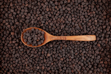 Uncooked Black chickpeas in wooden spoon on food background of chickpeas. Design element, selective focus