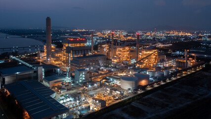 Obraz premium Aerial view coal power plant station at night, Power plant and coal storage heavy industrial coal powered electricity plant with pipes and smoke.