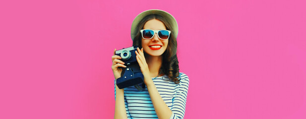 Summer portrait of happy smiling young woman photographer with vintage film camera on colorful pink background