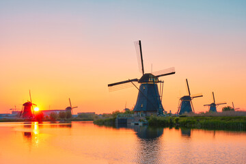 Fototapeta na wymiar Netherlands rural lanscape with windmills at famous tourist site Kinderdijk in Holland on sunset with dramatic sky