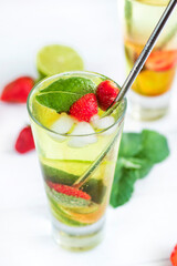 selective focus. cold summer drink with ice in a glass with a straw. Strawberry mojito cocktail in a glass with fresh mint, fresh strawberries and lime. detox refreshing drink on a light background. 