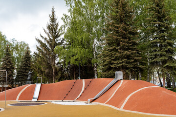 Metal slides on the playground, a modern city recreation park for the family, an orange mountain...