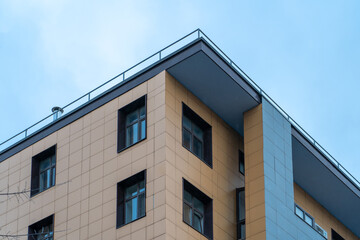 Close up view of corner of modern apartment building with balcony. View of fragment of facade and end face with balconies of house with windows