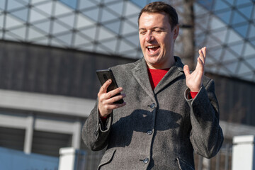Success and achievement, winnings, betting on sports. Excited overjoyed male in grey coat and red...