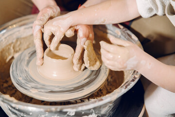 Mother with daughter makes vase in a potterystudio