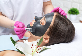 Obraz na płótnie Canvas Cosmetologist doing carbon peeling procedure to beautiful blue-eyed girl in a beauty salon. Hardware cosmetology treatment