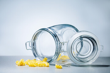 Remnants of pasta in empty glass jar on the table. Food crisis concept.