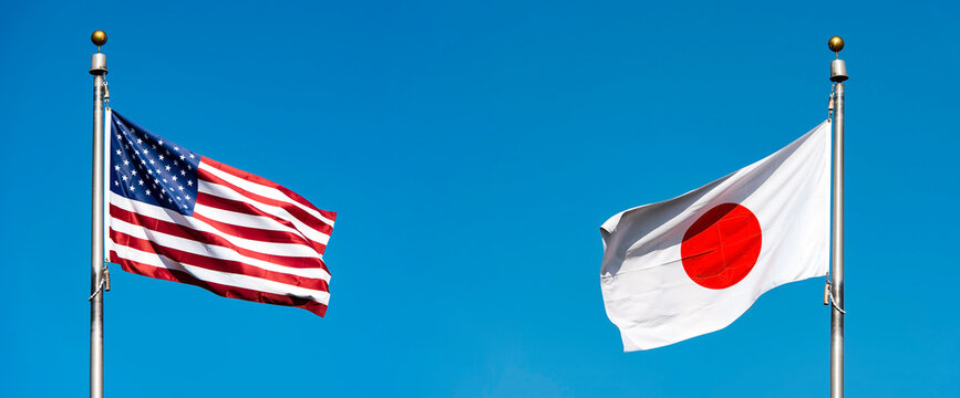 Flags of the USA and Japan against blue sky, concept political picture