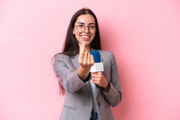 Young caucasian tv presenter woman isolated on pink background making money gesture
