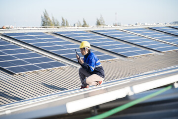 Fototapeta premium Asian technician installing inspection or repair solar cell panels on background field of photovoltaic solar panels solar cells on roof top factory.
