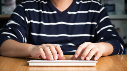
Business man typing on computer keyboard while working or using internet for online shopping and social network at wooden table. Laptop device and Wireless technology concept.