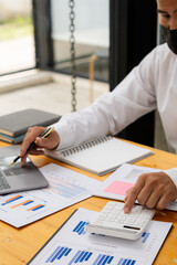 financial concept close-up businessman holding a graph pen press a calculator And make money by writing reports, memos and analyzing vertical image business documents.