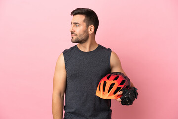 Young cyclist man isolated on pink background looking to the side - obrazy, fototapety, plakaty