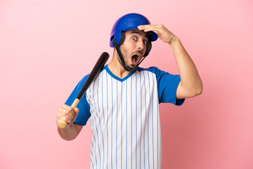 Baseball player with helmet and bat isolated on pink background doing surprise gesture while looking to the side