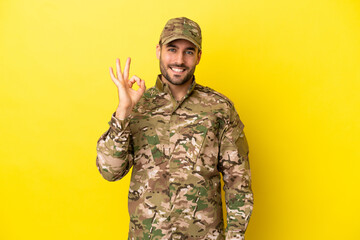Military man isolated on yellow background showing ok sign with fingers