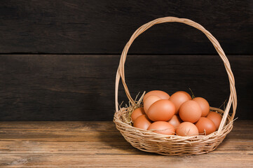 Organic chicken eggs in a basket fresh from the farm, laid on a wooden table, rustic atmosphere.