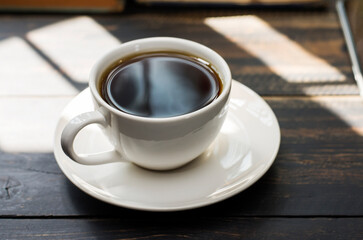 White coffee cup with black coffee or tea. put on desk or reading table - top view