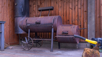 Vintage drum barrel charcoal BBQ in garden. Old barbeque outside in garden. Retro flaming coals offset smoker BBQ.