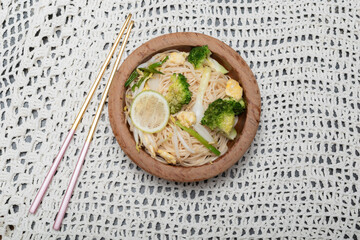 Healthy vegetarian food stir fried Chinese noodles on white fabric background.