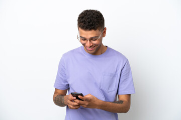 Young caucasian Brazilian man isolated on white background sending a message with the mobile