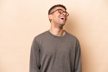 Young Brazilian man isolated on beige background laughing