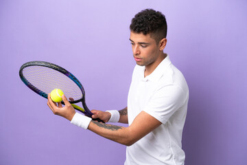 Young Brazilian man isolated on purple background playing tennis
