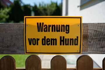 Ein gelbes Schild mit einem deutschen Text Warnung vor dem Hund. Vorsicht.