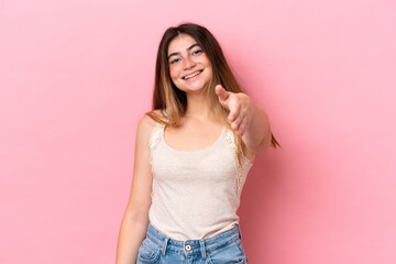 Young caucasian woman isolated on pink background shaking hands for closing a good deal