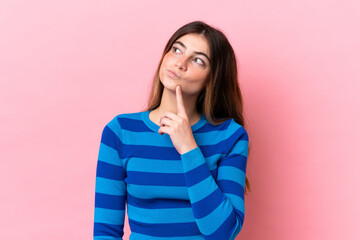 Young caucasian woman isolated on pink background having doubts while looking up