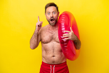 Middle age caucasian man holding inflatable donut isolated on yellow background thinking an idea...