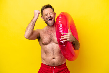 Middle age caucasian man holding inflatable donut isolated on yellow background celebrating a...