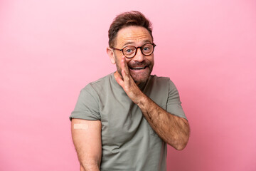 Middle age man wearing a band aids isolated on pink background whispering something