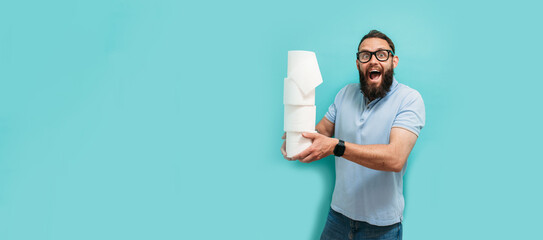 Attractive young caucasian guy holds several rolls of toilet paper in his hands, toilet paper...