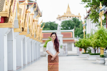 Portrait Asia woman wearing traditional dress of Thailand walking in temple for relaxation and meditation