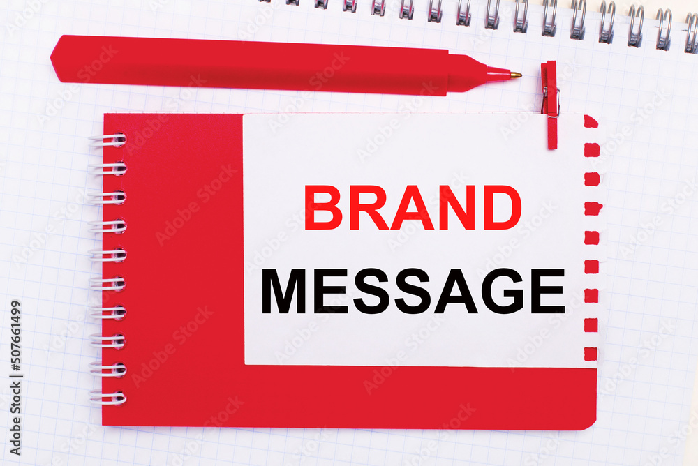 Poster on a white notepad, a red pen, a red notepad and a white sheet of paper with the text brand message