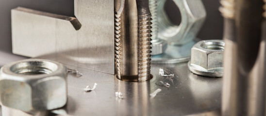 Thread tap drill steel billet with drill bit on background. Working cutter.