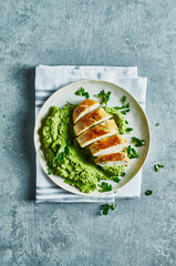 Chicken breast with pea puree on a plate. Top view
