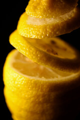 Fototapeta na wymiar Sliced citron falling into pieces on black background