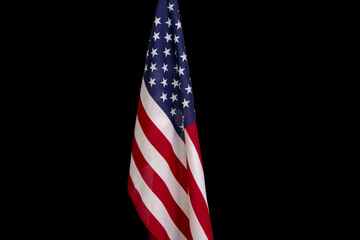 The American flag is mounted on a flagpole, black background, medium plan.