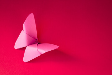 Pink paper butterfly origami isolated on a red background