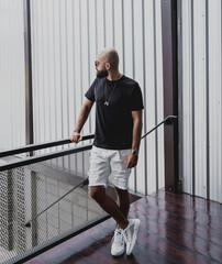 A young man in t-shirt and shorts on the stairs at city streets