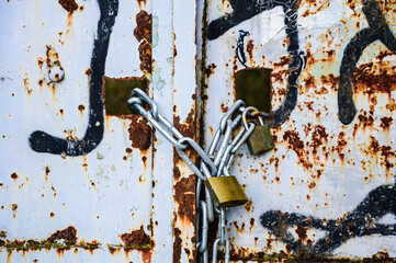 Rusty lock on the gate of a small gray container close-up.