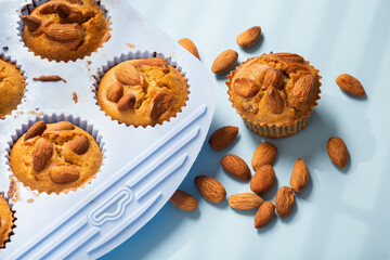 Set of various baking ingredients - flour, eggs, sugar, butter, nuts, kitchen utensils and cupcake baking dish on white background. Top view. Copy space