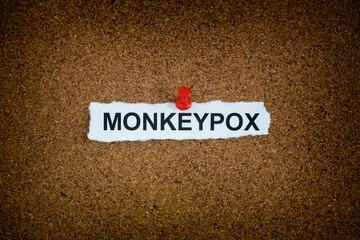 A piece of paper with the word Monkeypox on it pinned to a cork board