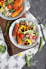 A light lunch of a salad of cucumbers, radishes, cherry tomatoes, lettuce, micro greens and toasted fish sticks.