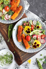 A light lunch of a salad of cucumbers, radishes, cherry tomatoes, lettuce, micro greens and toasted fish sticks.